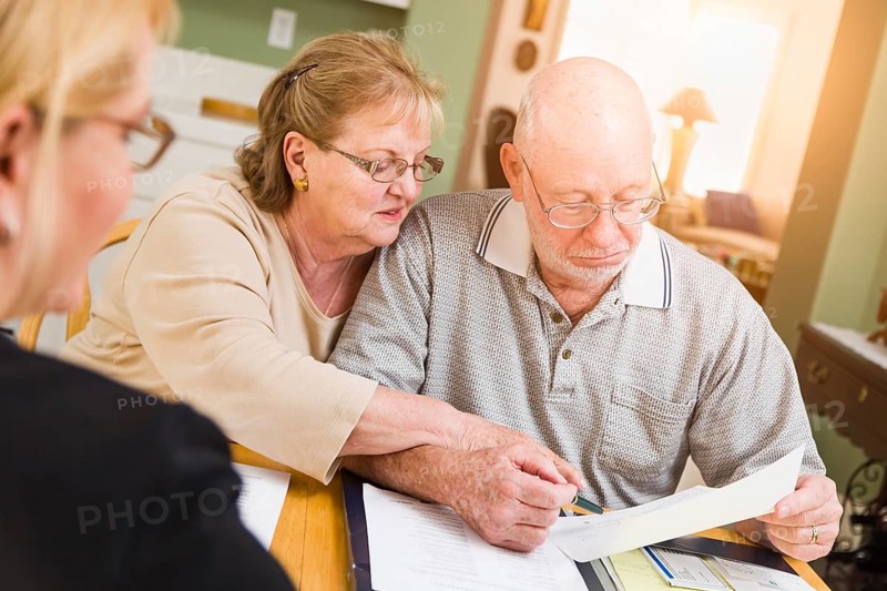 Senior adult couple going over documents in their home with agent at signing