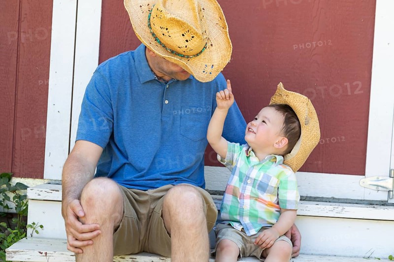Playful young caucasian father and mixed-race chinese son wearing cowboy hats