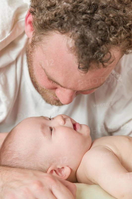 mixed-race chinese and caucasian baby boy laying in bed with his father