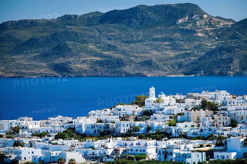 View of Plaka village with traditional Greek church and white painted houses and ocean coast