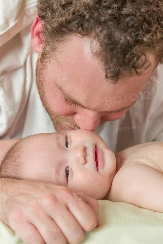 mixed-race chinese and caucasian baby boy laying in bed with his parents
