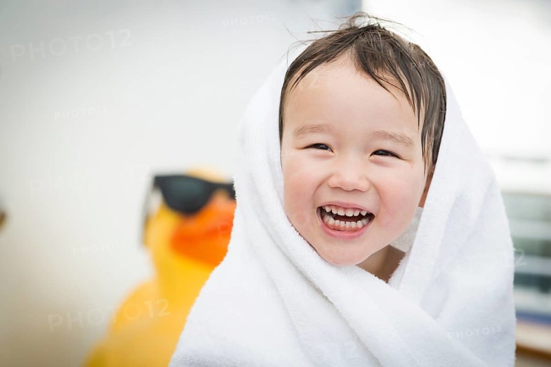 mixed-race boy having fun at the water park with large rubber duck in the background