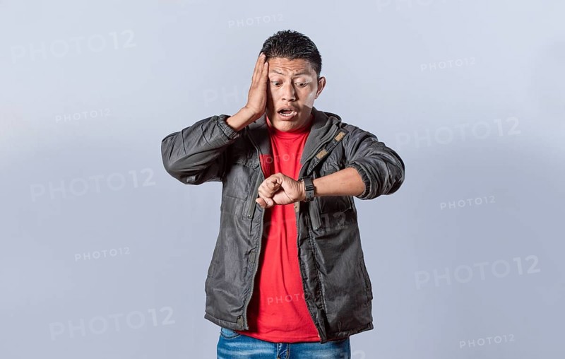 Young man in jacket looking at the watch time worried