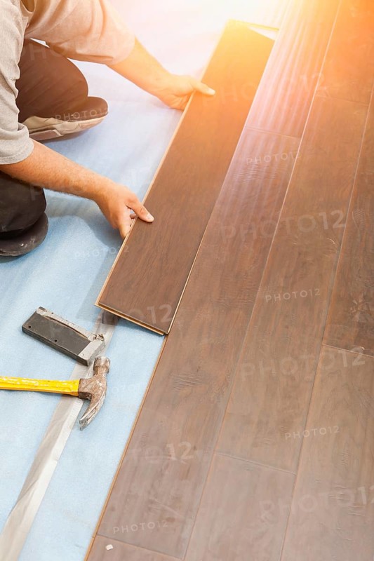 Man installing new laminate wood flooring abstract