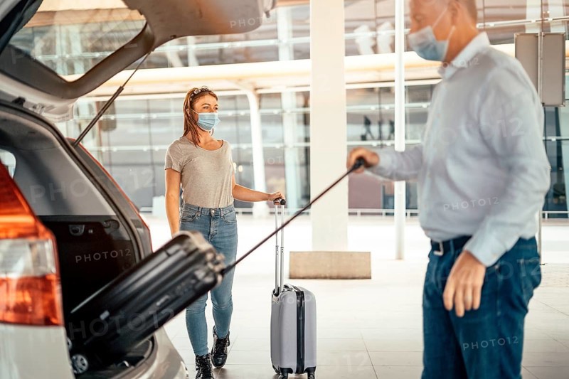 Thinking traveling woman waiting for her luggage being taken out from the taxi or Uber car trunk
