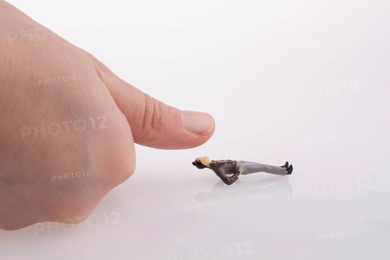 Hand threatening to smash human figure on a white background