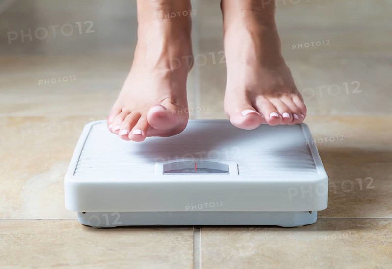 Woman floating slightly above surface of weight scale