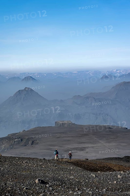 Two hikers on trail through volcanic landscape