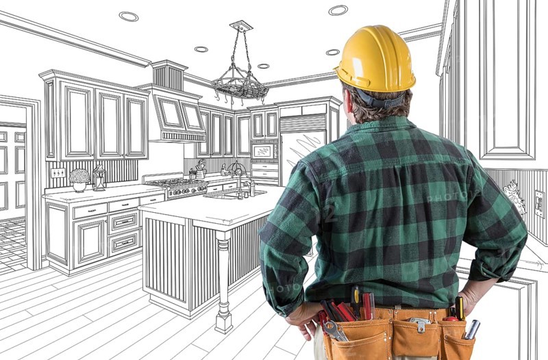 Male contractor with hard hat and tool belt looking at custom kitchen drawing on white