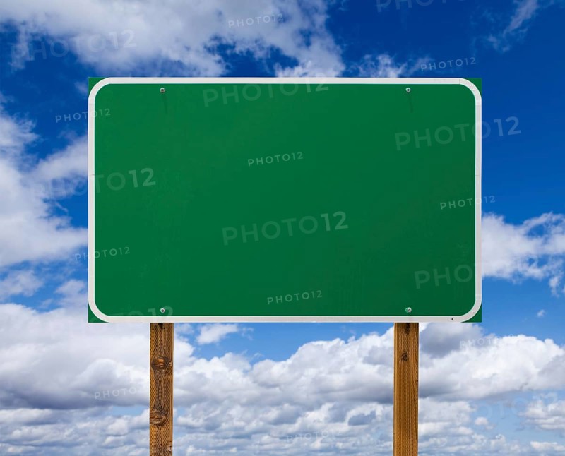 Blank green road sign with wooden posts over blue sky and clouds