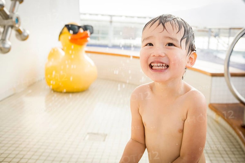 mixed-race boy having fun at the water park with large rubber duck in the background