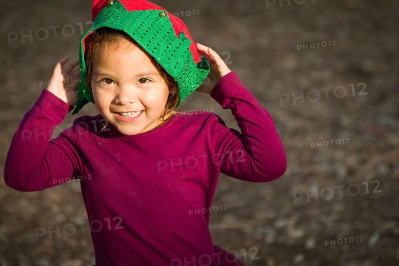 Cute mixed-race young baby girl having fun wearing christmas hat outdoors