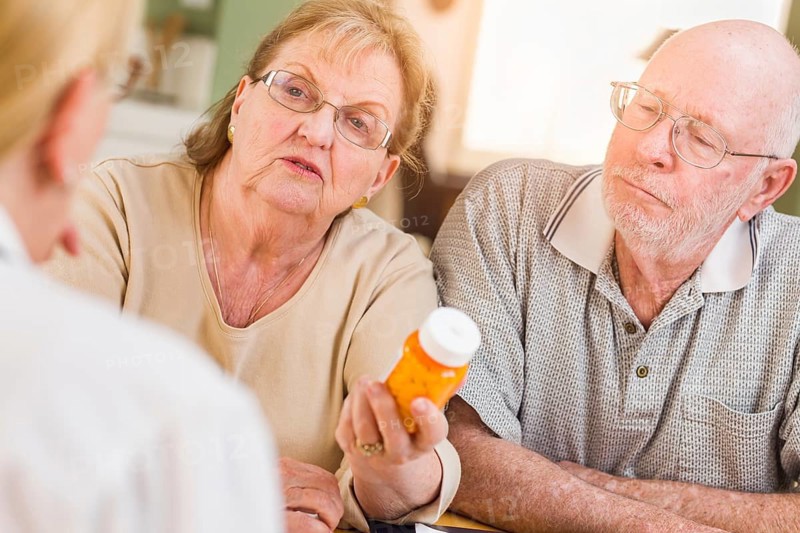 Doctor or nurse explaining prescription medicine to senior adult couple