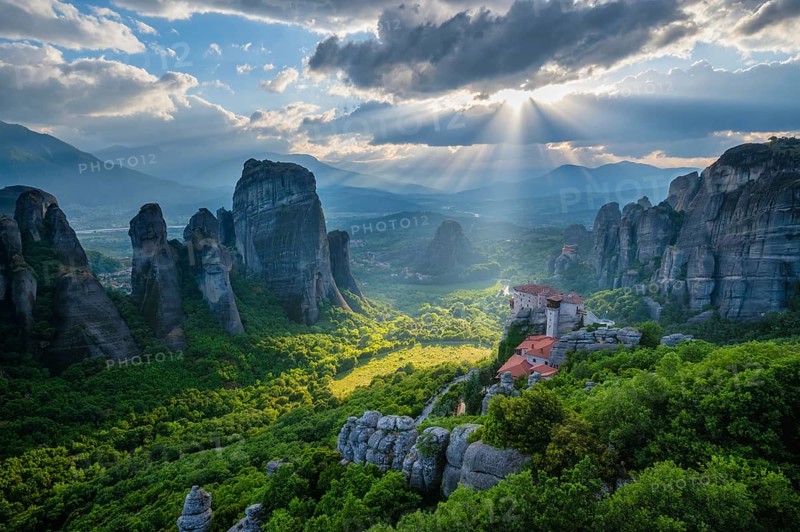 Sunset over monastery of Rousanou and Monastery of St. Nicholas Anapavsa in famous greek tourist destination Meteora in Greece on sunset with sun rays and lens flare and dramatic sky