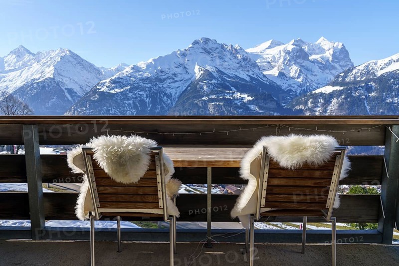 Chairs with fur on balcony in front of mountain panorama