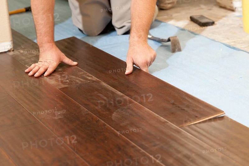Man installing new laminate wood flooring abstract