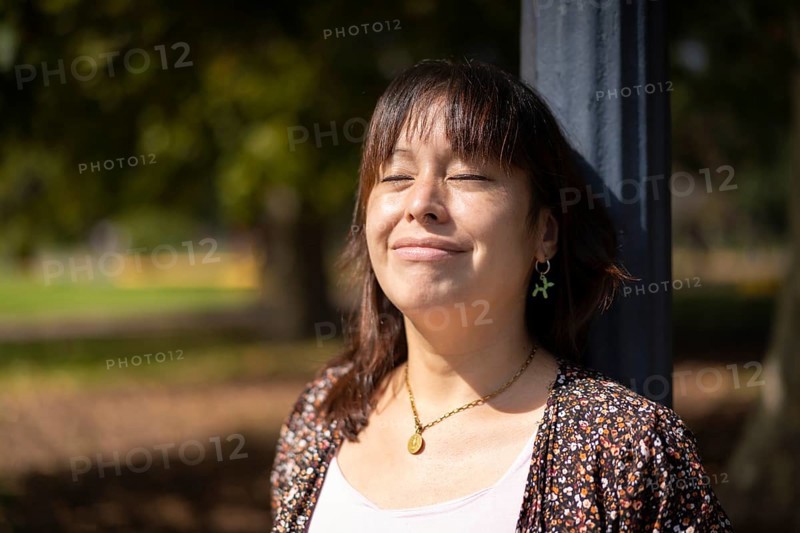 Portrait of a young Latin woman in a park leaning on a lamppost