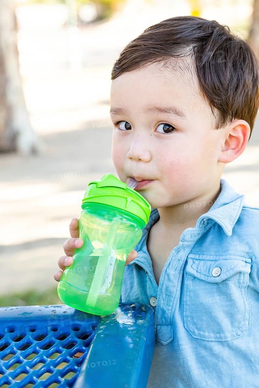Chinese and caucasian boy drinking water at playground