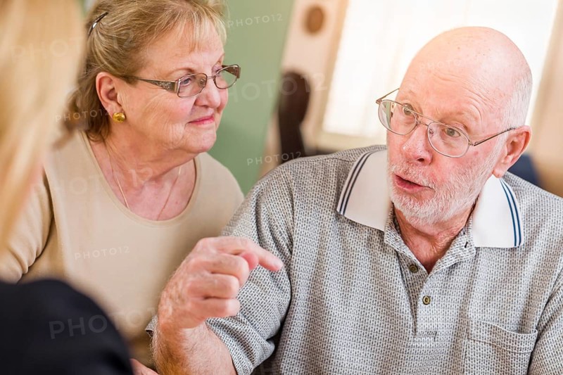 Senior adult couple going over documents in their home with agent at signing