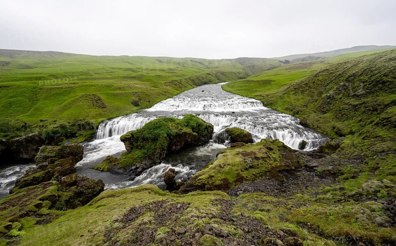 Wide waterfall between green meadows
