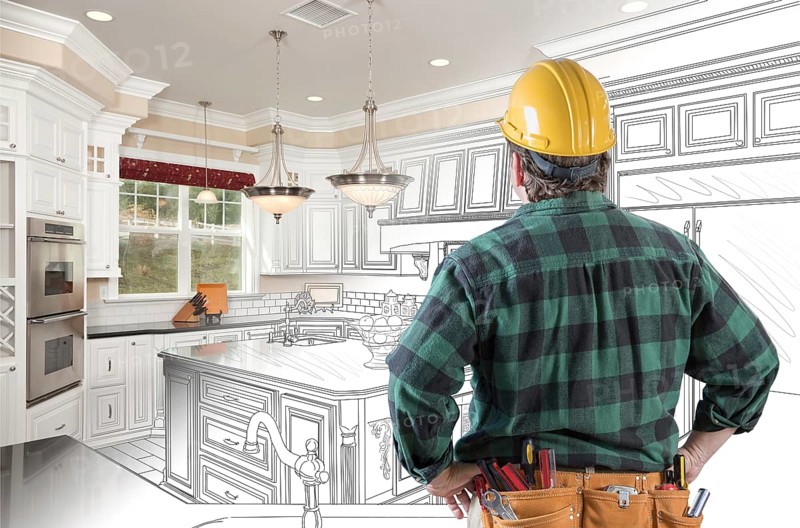 Male contractor with hard hat and tool belt looking at custom kitchen drawing photo combination on white
