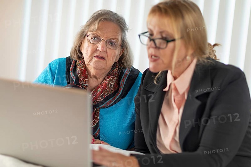 Woman helping senior adult lady on laptop computer