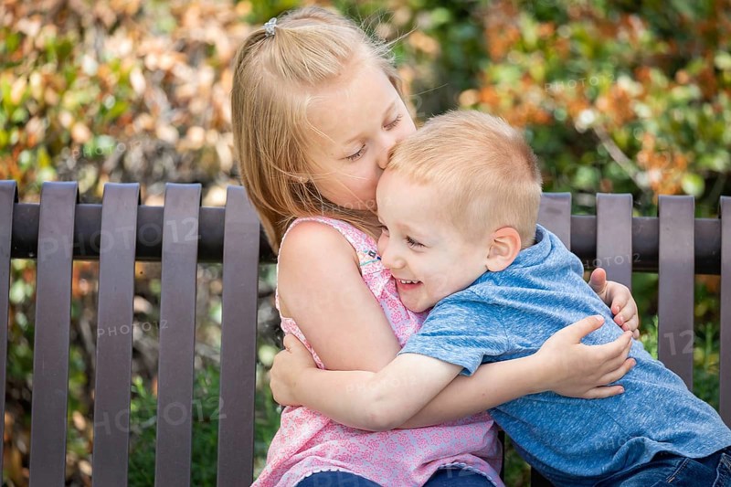Young sister and brother having fun on the bench at the park