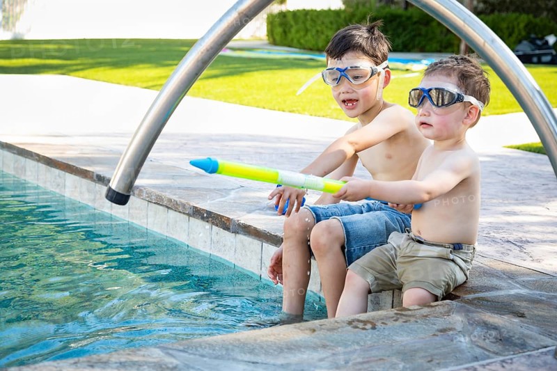 Young mixed-race chinese and caucasian brothers wearing swimming goggles playing at the pool