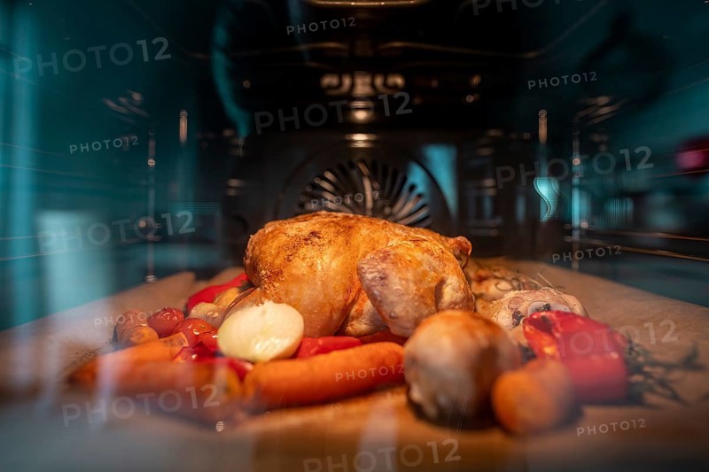 Crispy roasted chicken in a hot oven. Front view through the pane