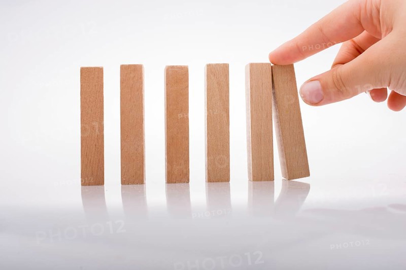 Hand holding wooden domino on a white background