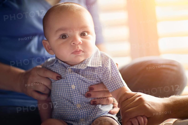 Happy mixed-race couple enjoying their newborn son in the light of the window