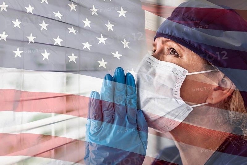 Prayerful stressed female doctor or nurse on break at window wearing medical face mask