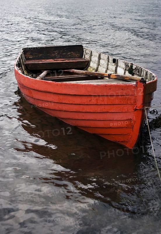 Leeres rote Ruderboot am Seeufer bei Regenwetter