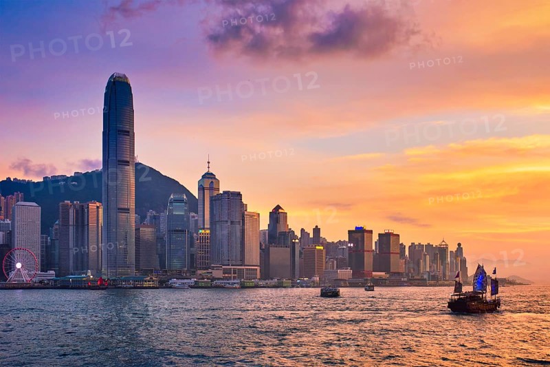 Hong Kong skyline cityscape downtown skyscrapers over Victoria Harbour in the evening with ferry boat and junk boat on sunset. Hong Kong