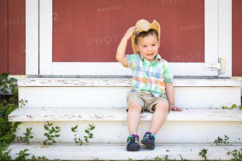 Young mixed-race chinese and caucasian boy wearing cowboy hat relaxing on the steps