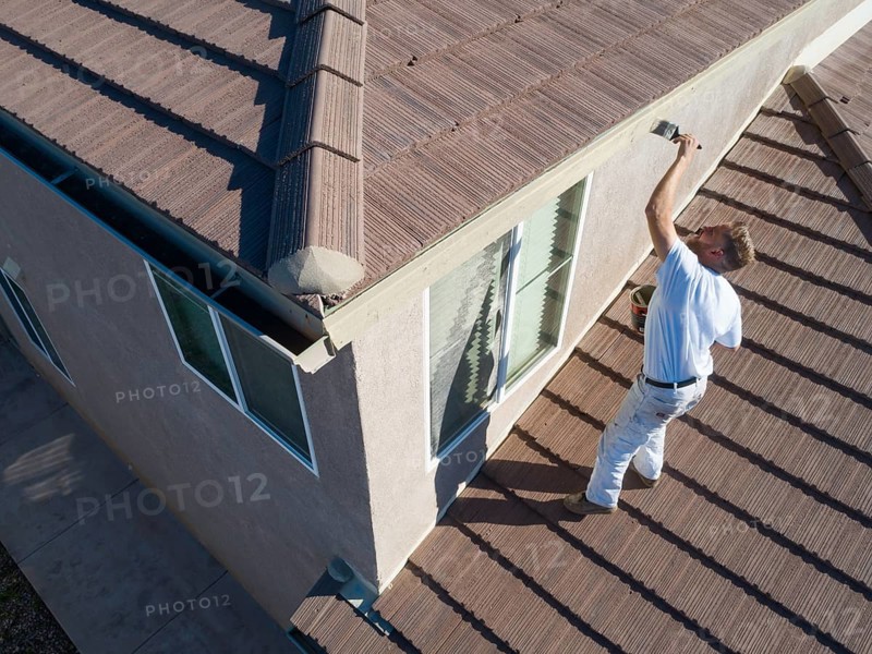 Professional painter using A brush to paint house facade