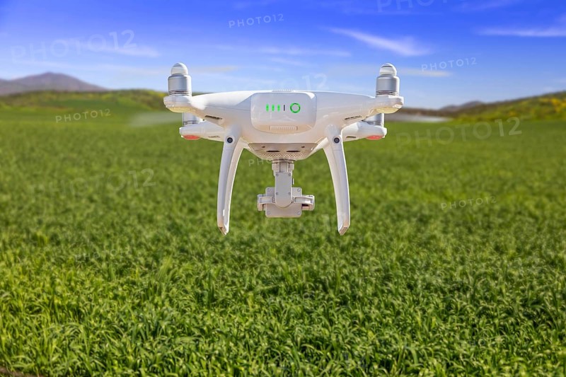 Drone unmanned aircraft flying and gathering data over country farmland