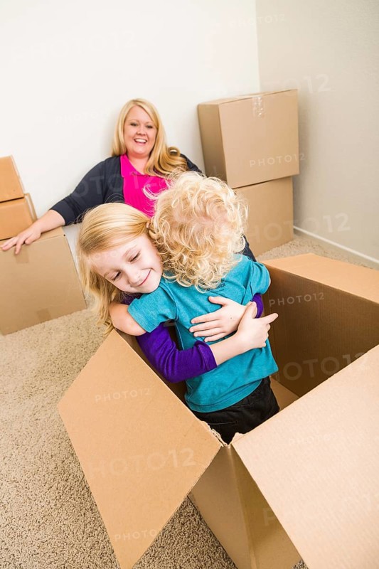 Playful young family in empty room playing with moving boxes
