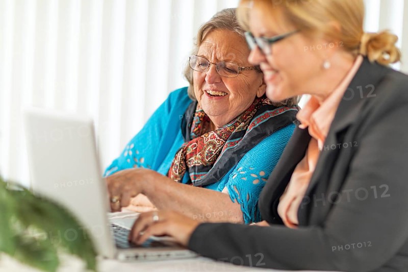 Woman helping senior adult lady on laptop computer