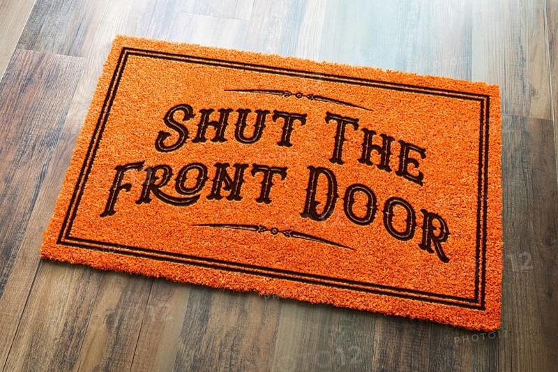 Shut the front door halloween orange welcome mat on wood floor background