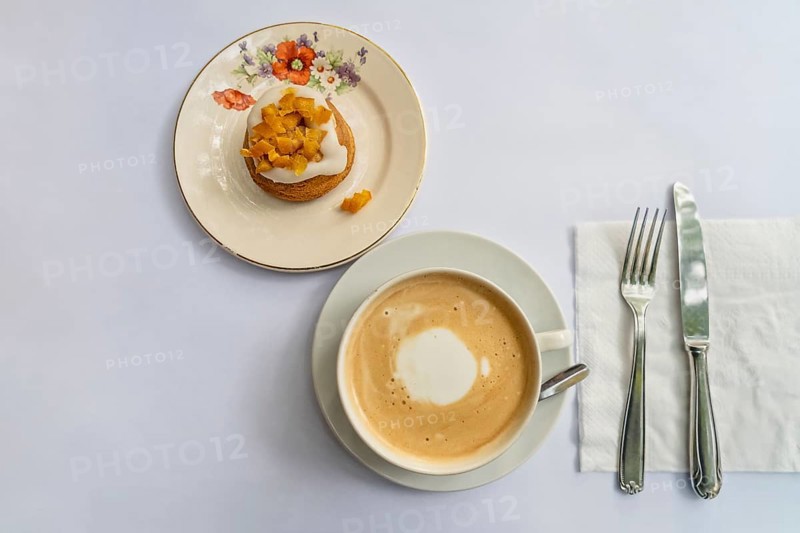 Top view of a latte and an orange cupcake on vintage crockery