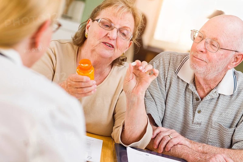Doctor or nurse explaining prescription medicine to senior adult couple
