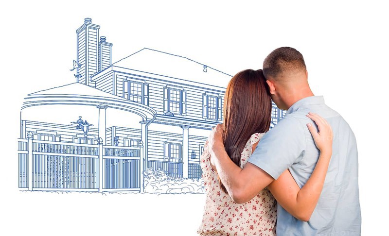 Embracing military couple looking at house drawing on white