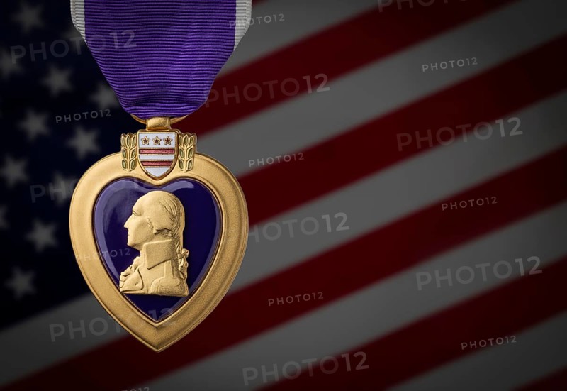Purple heart miltary merit medal against darkened american flag