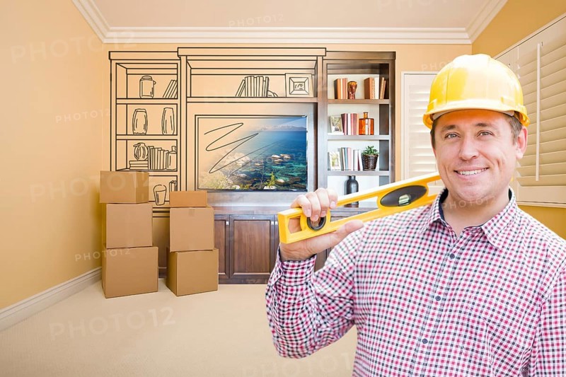 Male construction worker wearing hard hat in room with drawing of entertainment unit on wall