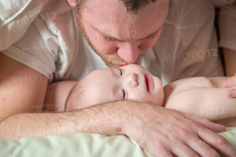 mixed-race chinese and caucasian baby boy laying in bed with his father and mother