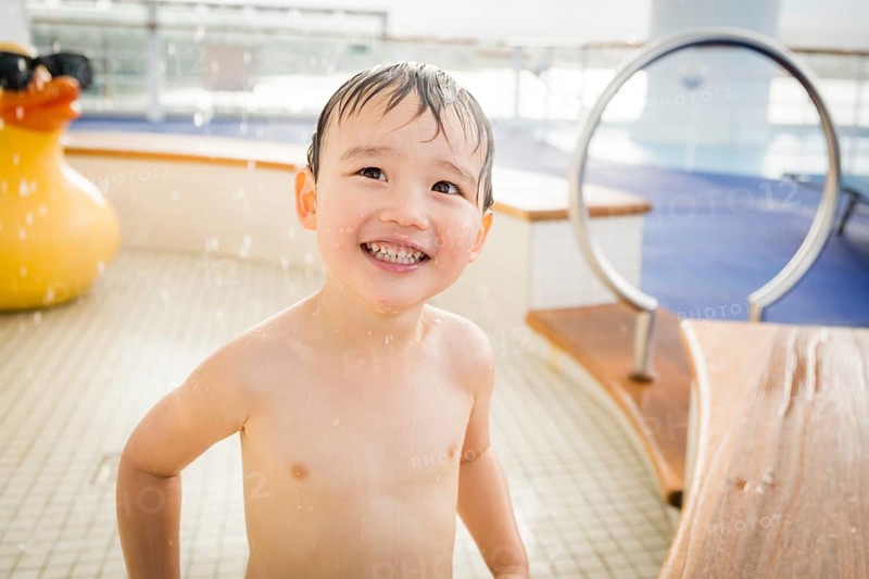 mixed-race boy having fun at the water park with large rubber duck in the background