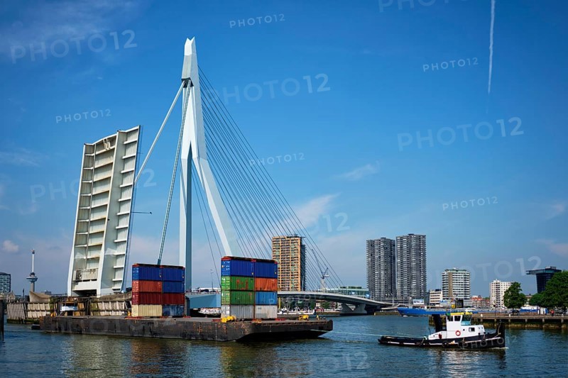Tug boat towing barge with containers under open bascule part of Erasmusbrug bridge in Nieuwe Maas river. Rotterdam
