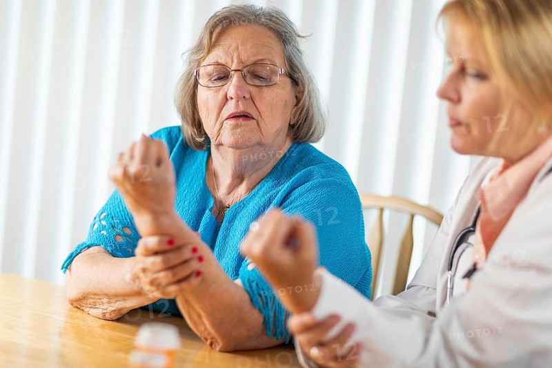 Female doctor talking with senior adult woman about hand therapy