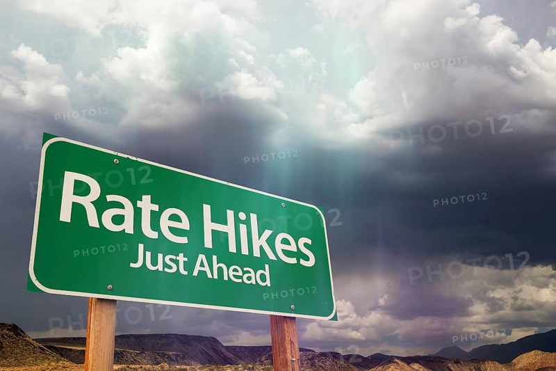 Rate hikes green road sign over dramatic clouds and sky